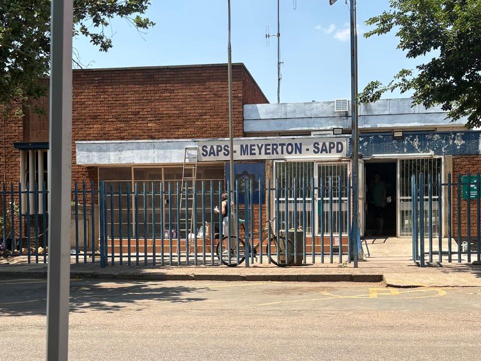 Meyerton police station before the project, with faded palisade fence and flaking paint on the entrance wall