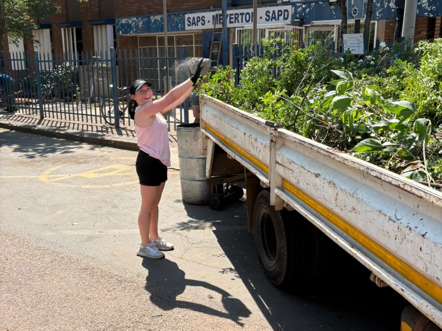 Volunteer loading garden waste onto a truck outside the police station